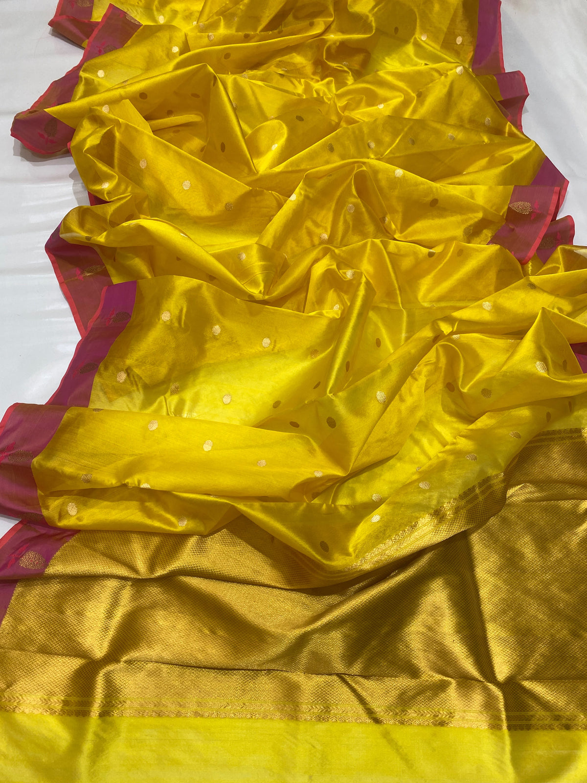 Turmeric yellow Chanderi Pattu silk saree draped to show its luminous body and raspberry pink border