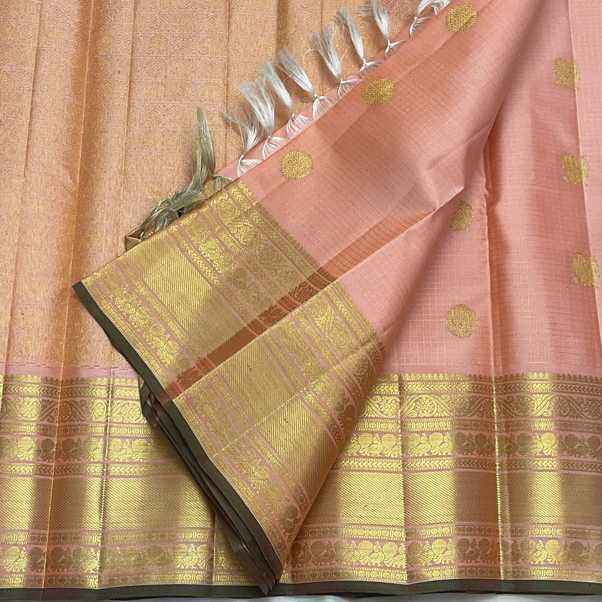 Peach pink and classic-gold Kanchipuram silk showing fine grid work, ornate border and dense pallu weaving.