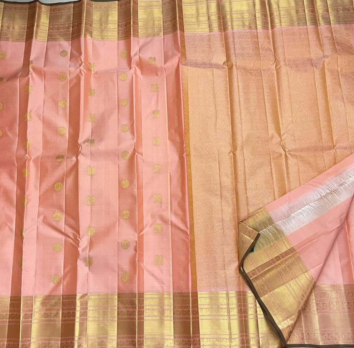 Handwoven peach-pink Pure Silk Kanchipuram saree with spaced gold buttas and a luminous broad zari border.