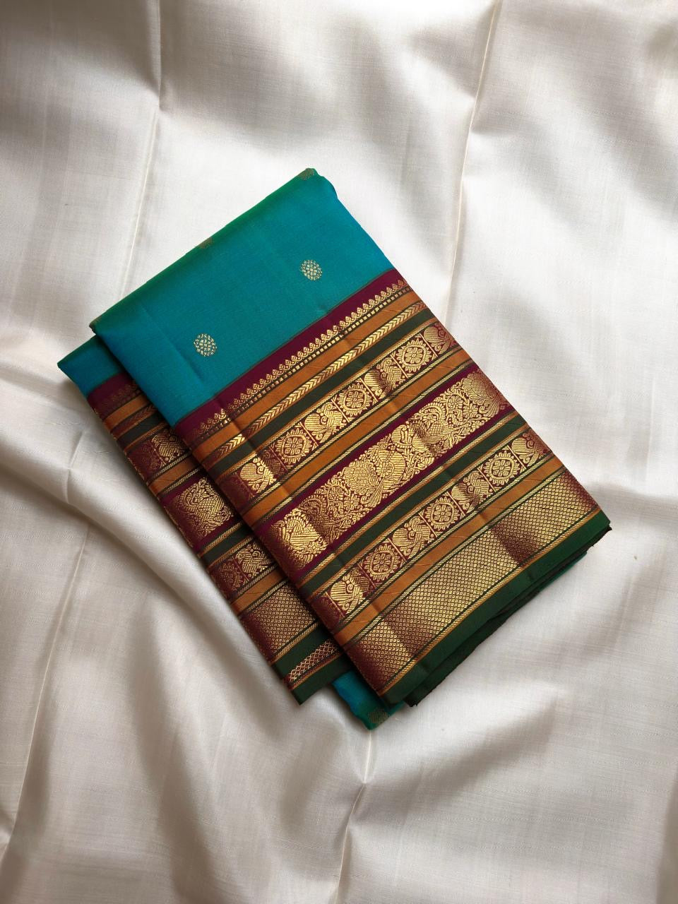 Peacock Blue-Green Pure Silk Kanchipuram Varisaipet saree with petite gold buttas and intricate stacked zari border.