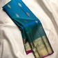 Peacock blue-green Kanjivaram saree with Rani-pink selvedge, gold zari Mayil motifs and temple-inspired Pettu
