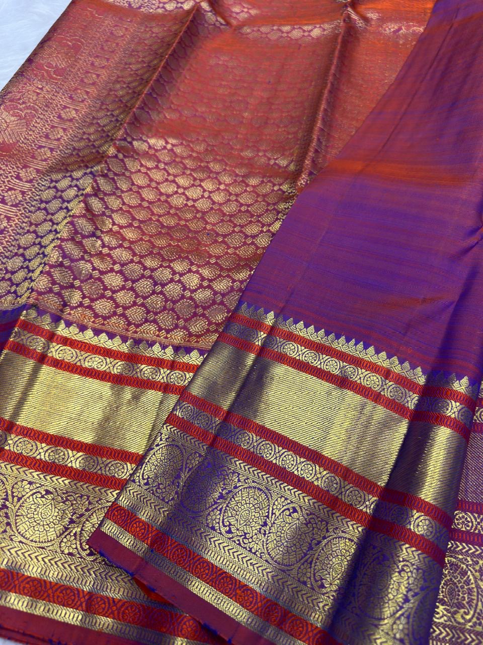 Detailed plum-red and purple contrast border with ornamental kodi butta work and gold zari bands.