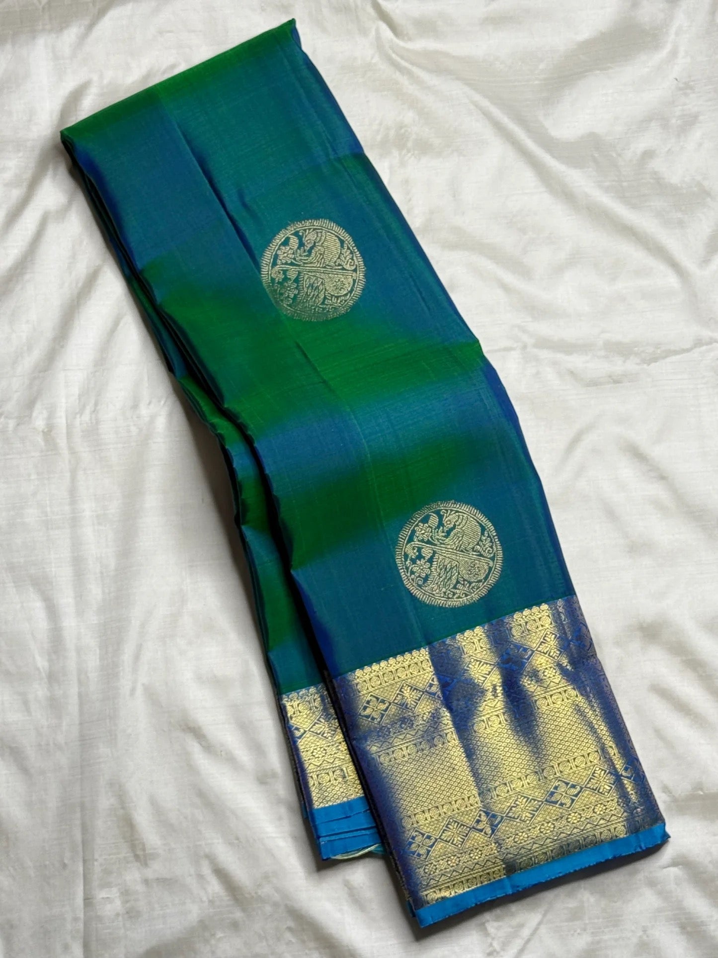 Open Peacock Neck Blue-Green Pure Silk Kanchipuram Butta saree with large Veena-Peacock gold zari medallions and Sky Blue border.