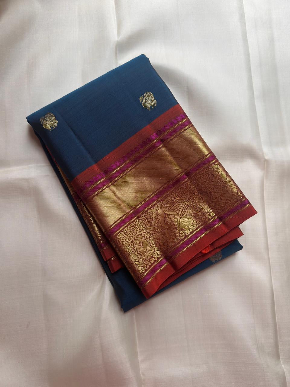 Close-up of antique gold zari Butta motifs on peacock blue Kanchipuram silk saree