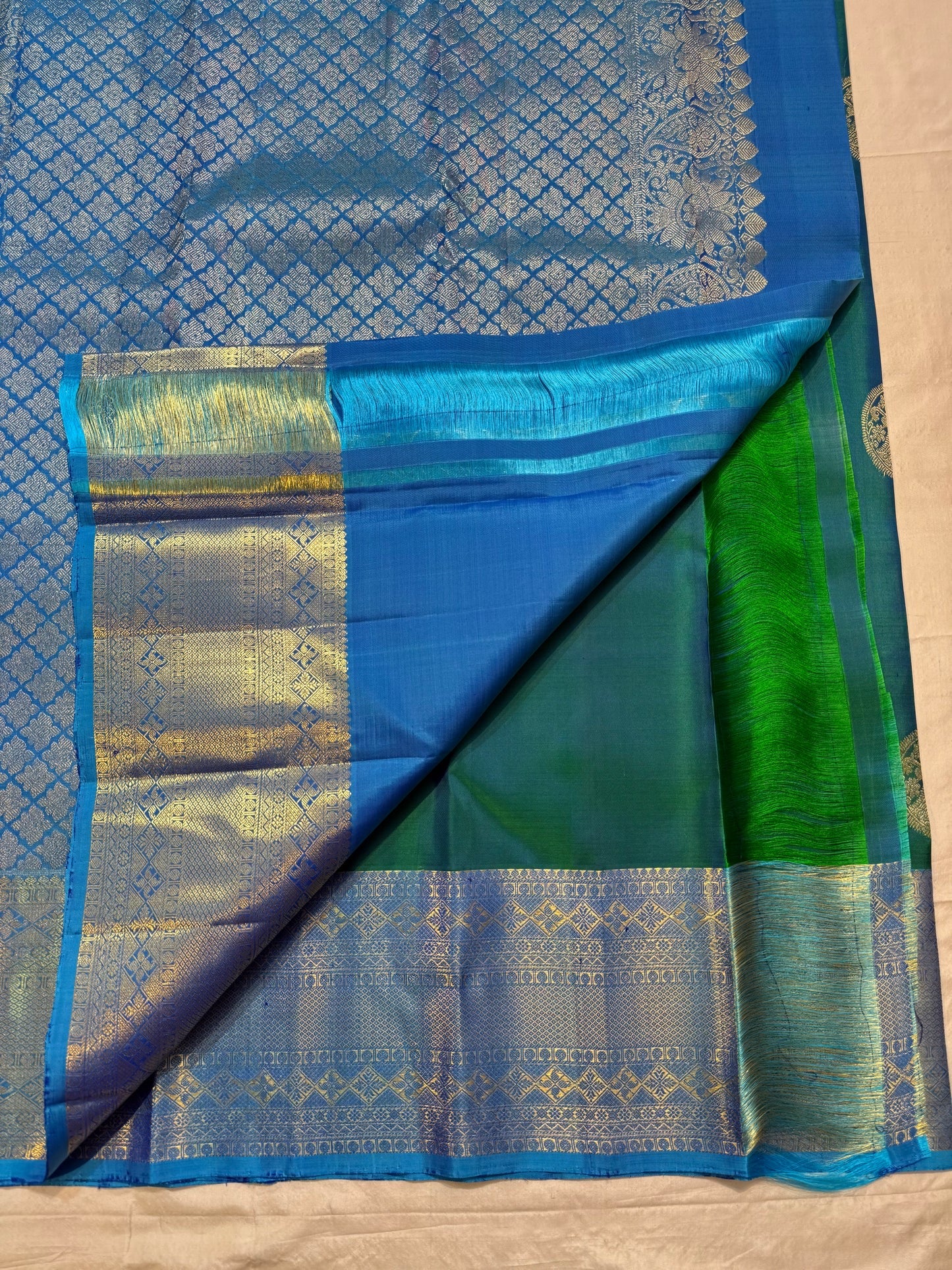 Folded Peacock Neck Blue-Green Pure Silk Kanchipuram Butta saree with Veena-Peacock medallion and geometric gold zari border.