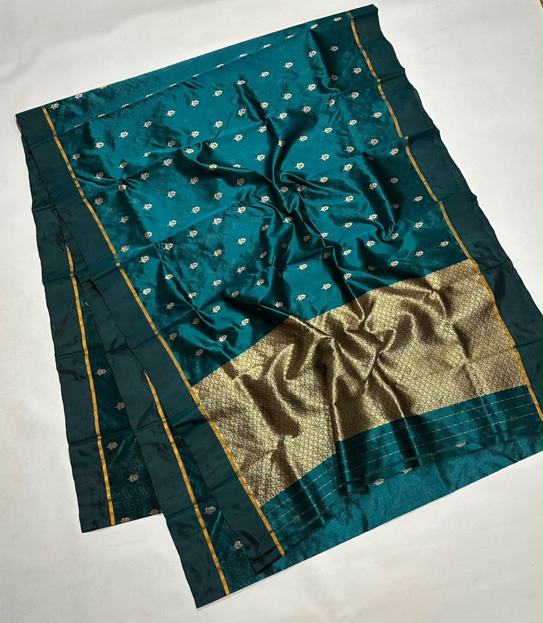 Deep teal saree border finished with a slender gold woven line.