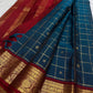 Fine gold Zari Kattam checks woven across the dark Peacock Teal pure silk body.