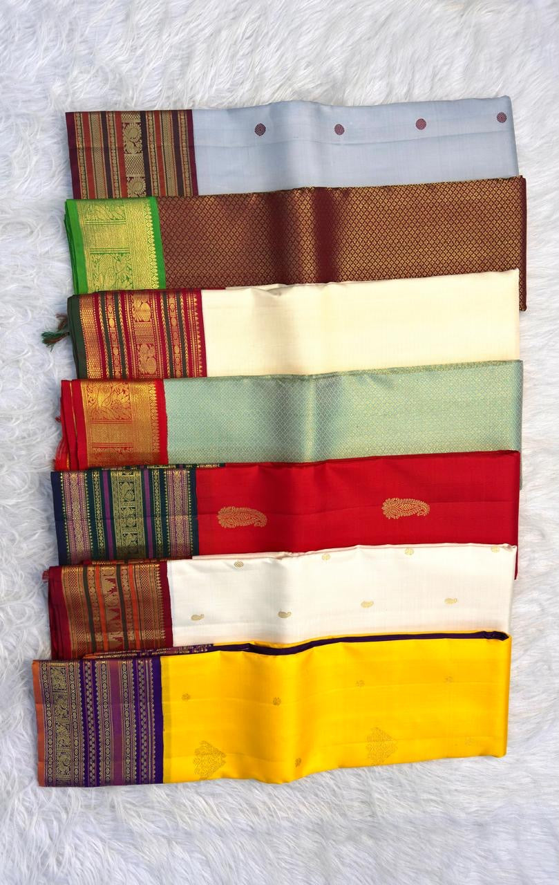 Overlapping folds of grey Kanchipuram silk showing Kalam body buttas and a gold zari border