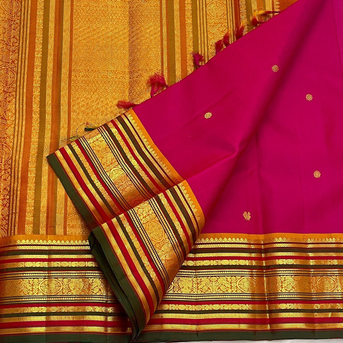 Close view of petite handwoven gold zari buttas on Raspberry Pink silk