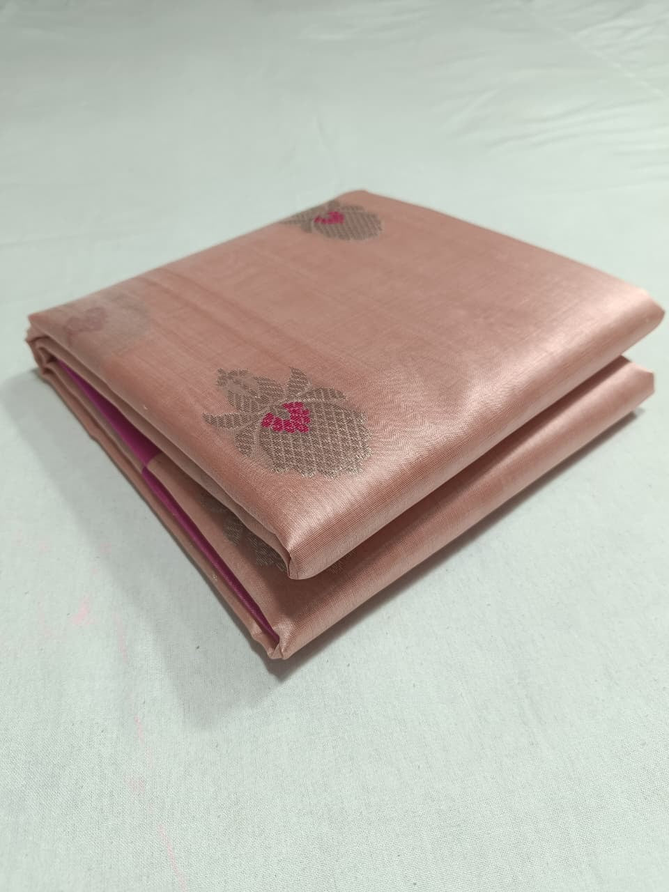 Close-up of the vivid Rani Pink accents within the silver floral buttas on a Blush Peach Chanderi saree