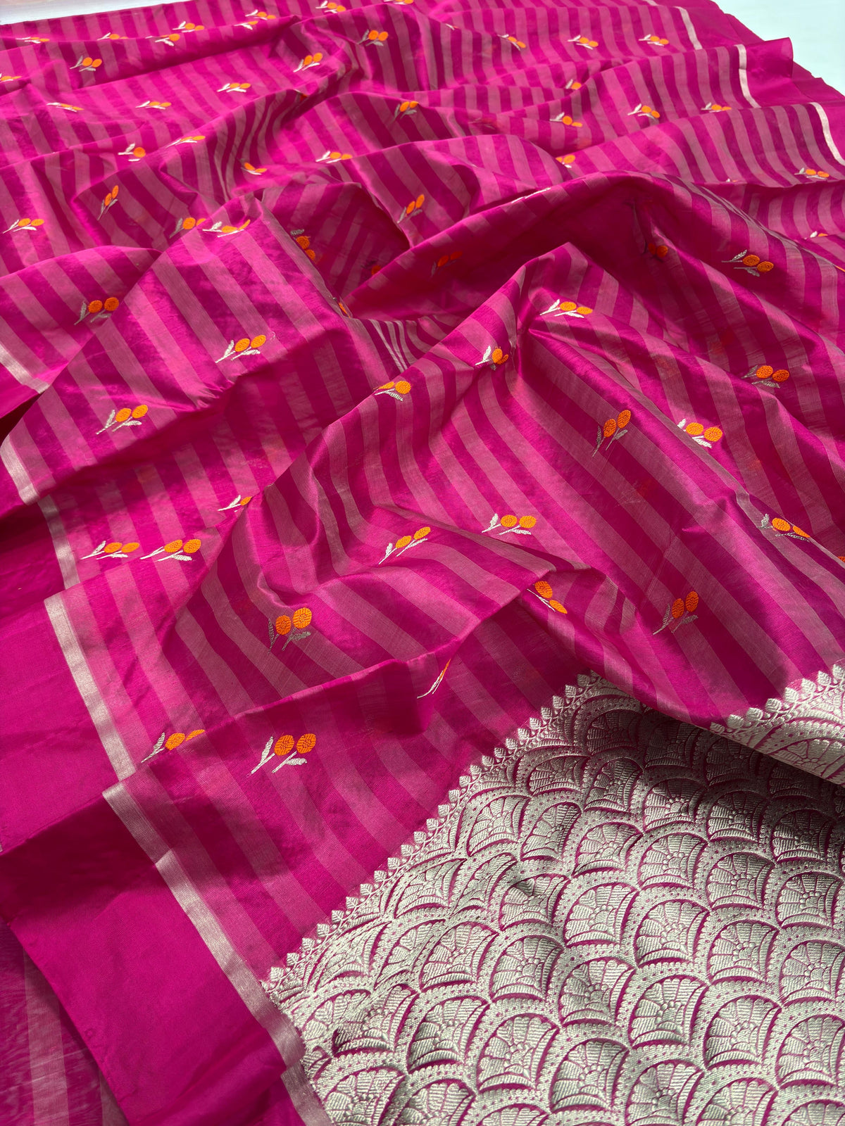 Close-up of small orange-and-ivory woven motifs on the Raspberry Pink striped Pattu Silk Chanderi saree.