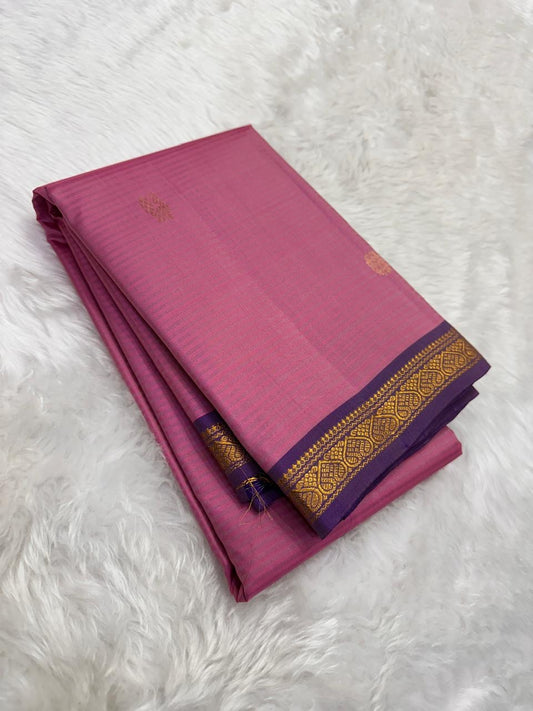 Folded rose pink Pure Kanchipuram Silk Saree with gold buttas and purple zari border on white fur background