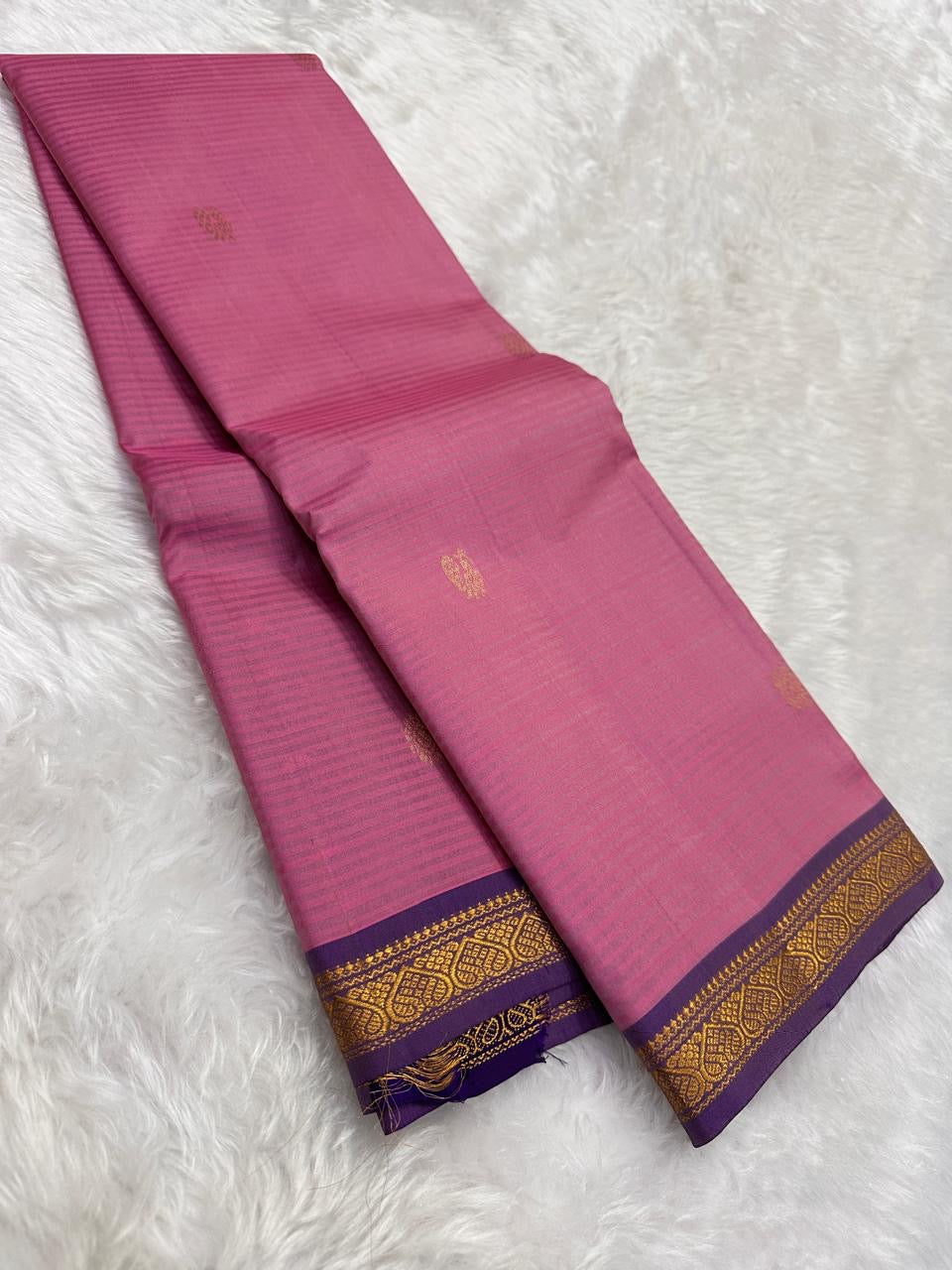 Rose pink Pure Kanchipuram Silk Saree drape with gold buttas and purple zari border on white fur background