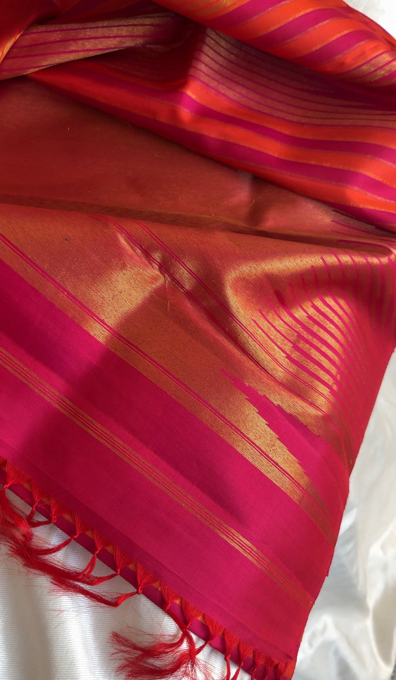 Handwoven pure silk Kanjivaram Ettukol saree in warm pink and orange.