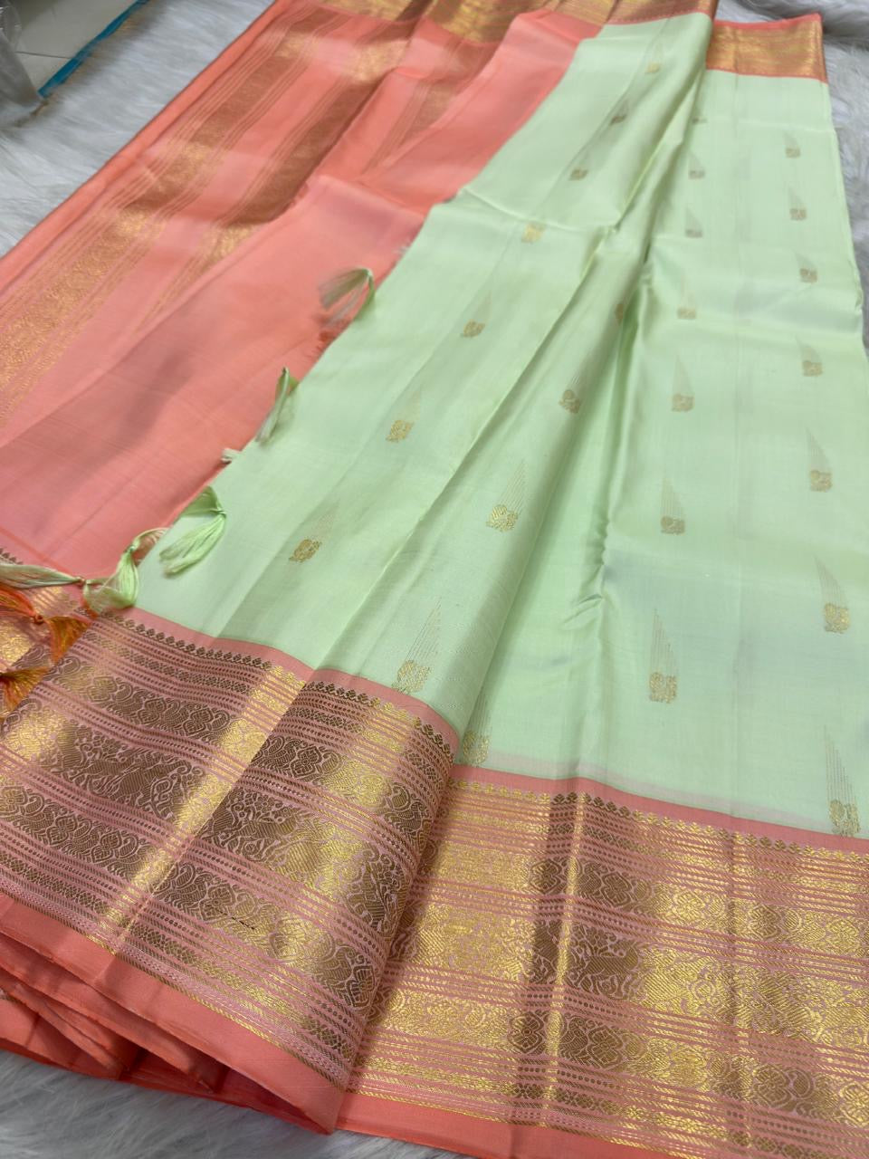 Tender pistachio-green Kanchipuram silk body showing generously spaced petite traditional gold zari buttas.