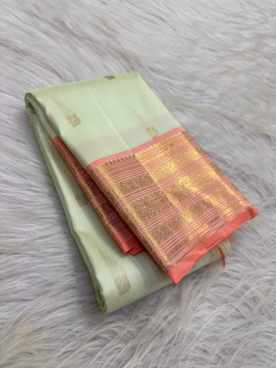 Close view of the lotus-petal peach pettu with layered seer lines and floral-paisley traditional gold zari work.