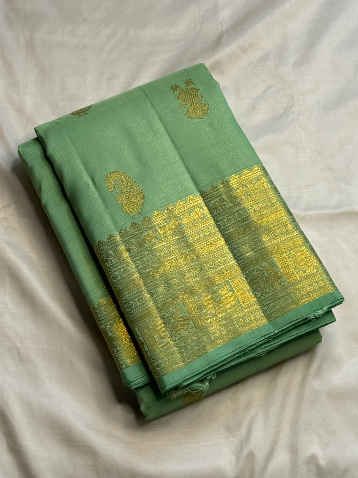 Fresh pistachio and lime-toned handwoven Kanchipuram silk with widely spaced traditional zari buttas.