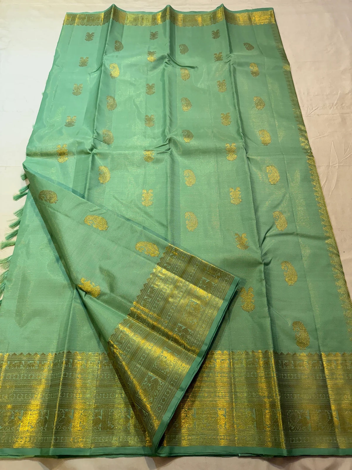 Detail of alternating Gandaberunda and paisley motifs woven across the pale-green silk body.