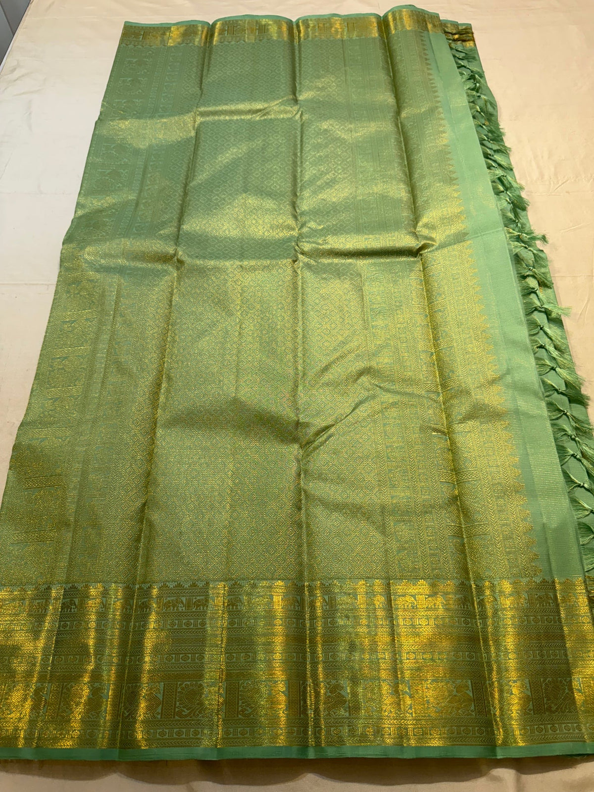 Green Pure Silk Kanchipuram saree showing elaborate gold-toned Gandaberunda and curved paisley motifs.
