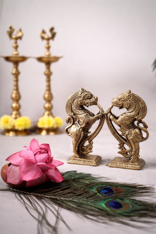 Pure solid brass Yazhi sculpture pair 5 inch height displayed with traditional brass kuthu vilakku lamps and floral bowl decor