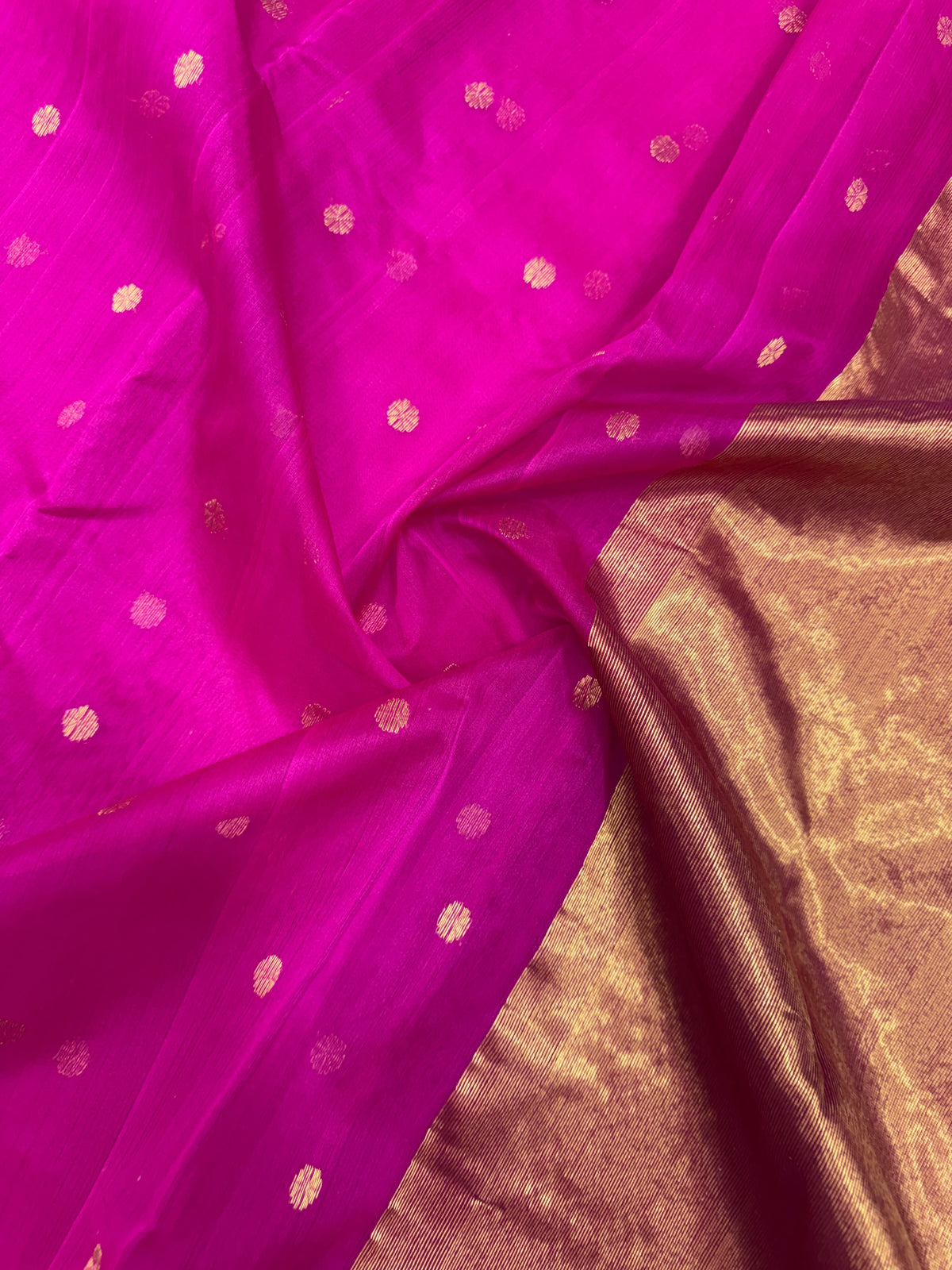 Detail of the purplish pink Chanderi silk body with small gold-toned buttas against the luminous gold-toned pallu
