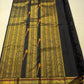 Black Kancheevaram silk saree with antique gold zari border and vermilion accents.