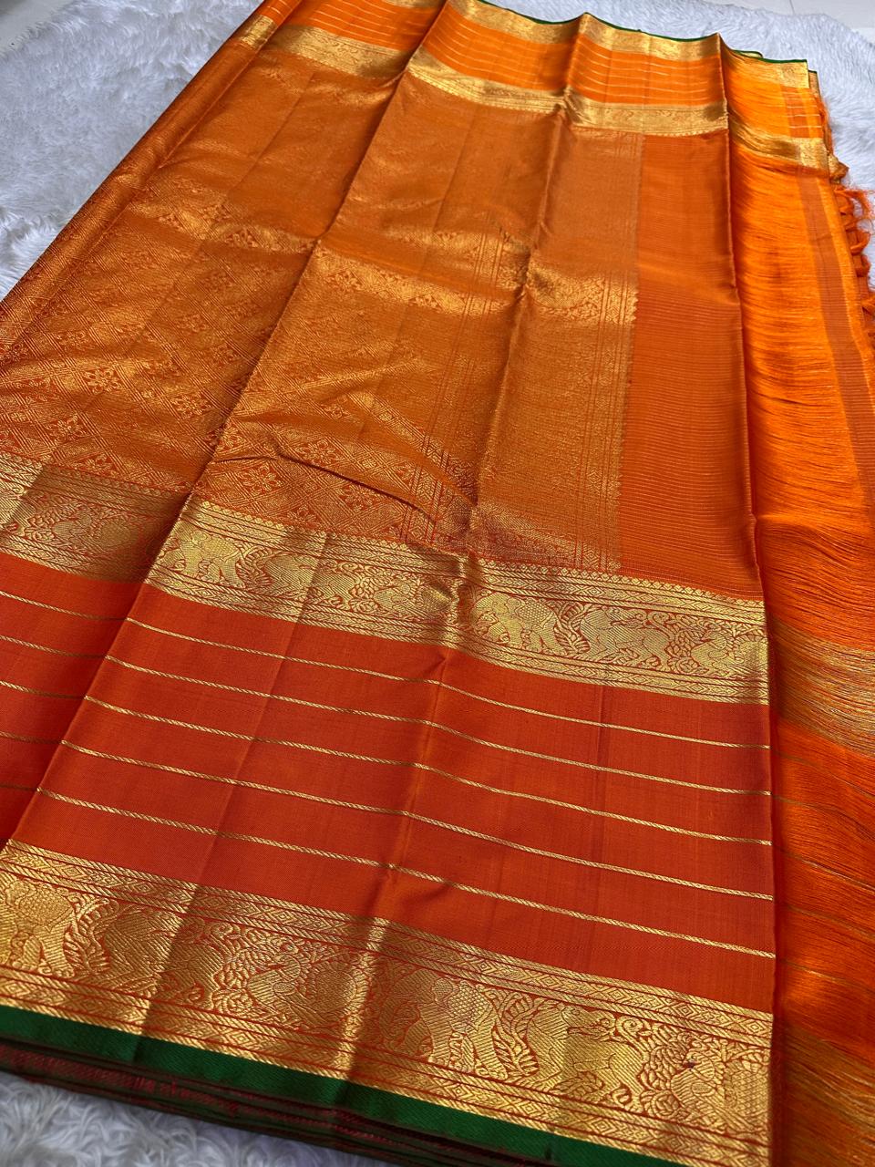 Close view of vermilion orange pure Kanchipuram silk saree with gold zari stripes and ornate zari border
