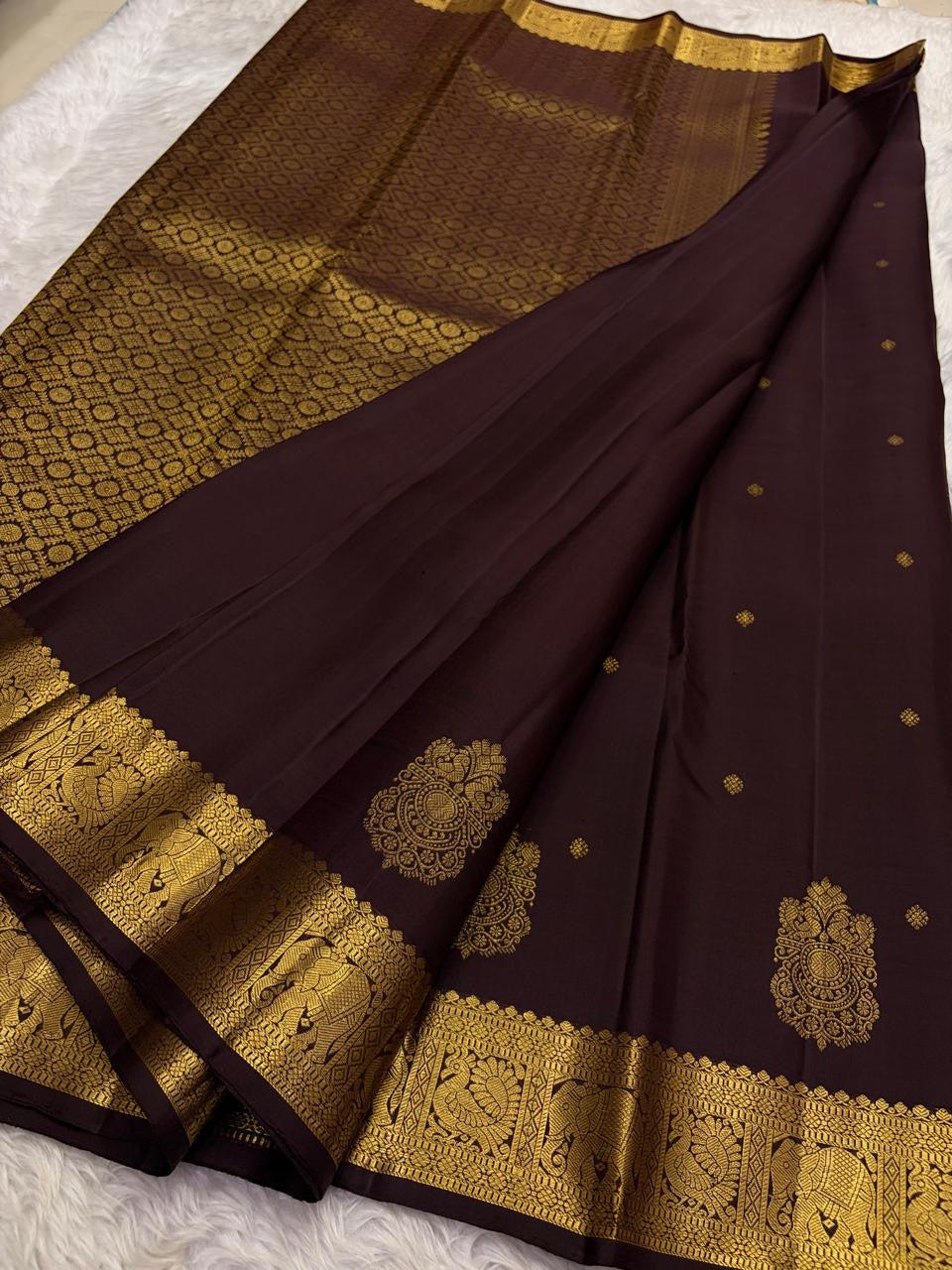 Ornate self-colour border of deep chocolate brown Kanjipuram saree with dense Maanga and floral antique gold zari array
