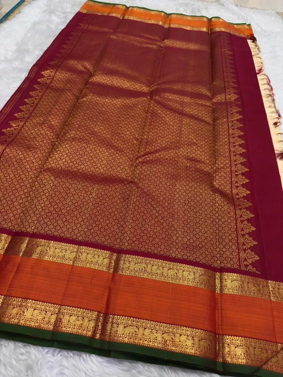 Folded warm ivory Kanjivaram silk saree with gold twin bird buttas and contrasting Korvai border.