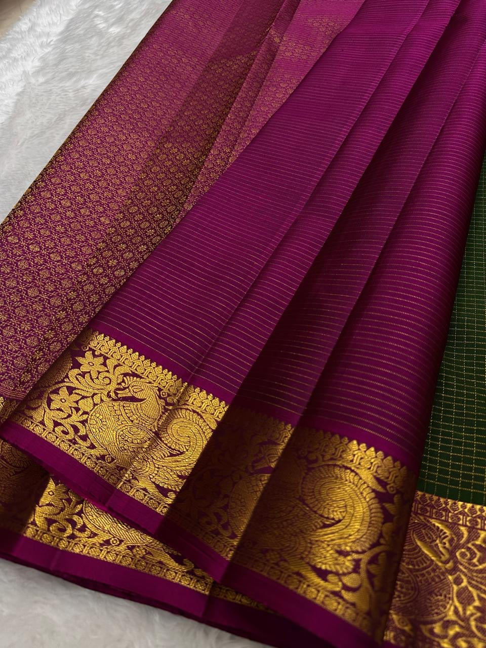 Raspberry pink peacock zari border detail on forest green Kanchipuram saree