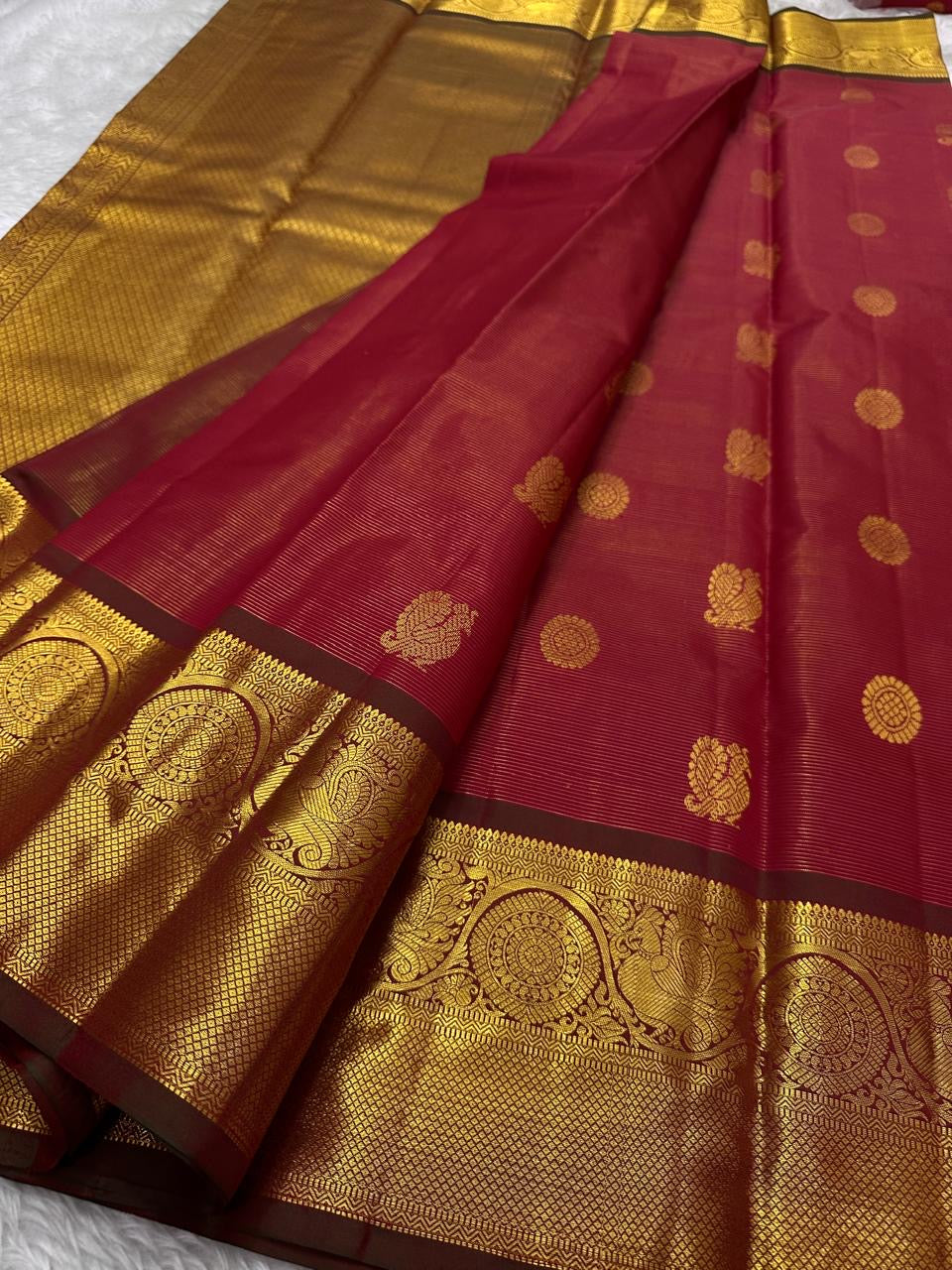 Full view of bright vermilion red with a luminous petal pink pallu Kanchipuram saree showing airy butta placement across the body.