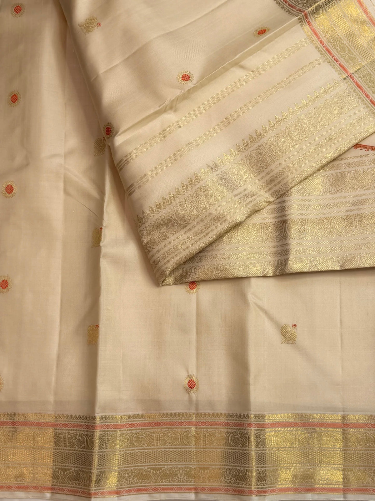 Close detail of the exclusively designed meenakari orange butta inside the zari-woven kamalam butta.
