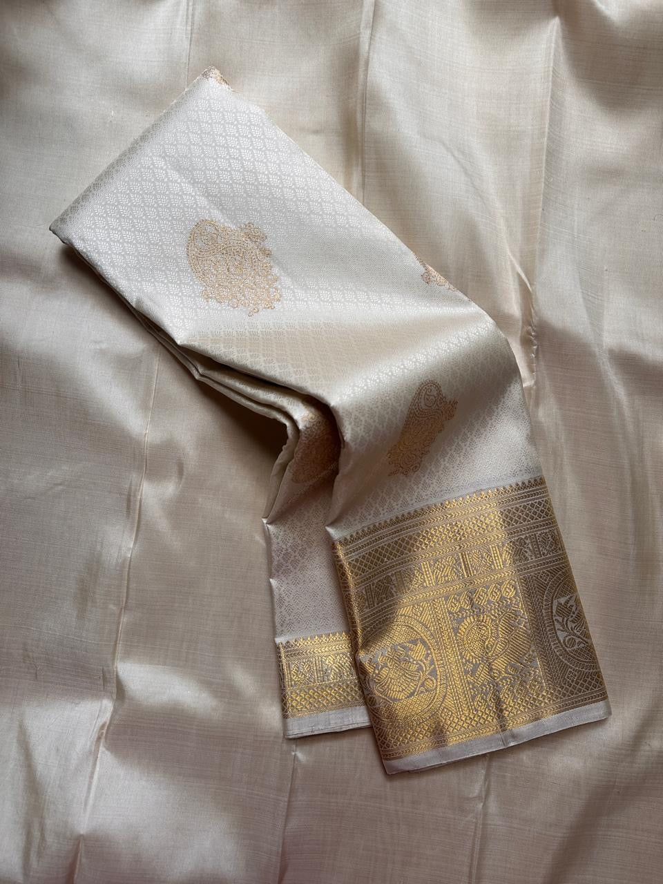 Ivory Pure Kanchipuram Silk Saree draped to show body with gold motifs and gold zari border.
