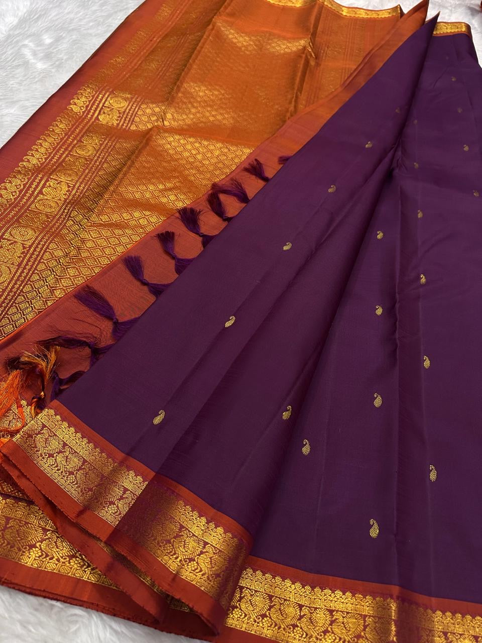 Close view of antique-gold paisley buttas on Muted Plum Purple Kanjivaram silk.