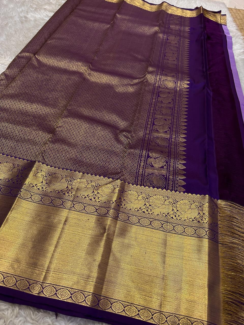 Close view of antique gold zari border and purple silk body on a Kanchipuram silk saree