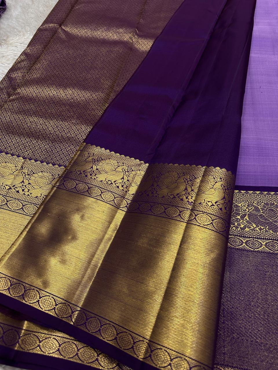 Pure Kanchipuram silk saree with purple body and wide antique gold zari pallu displayed open