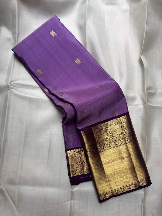 Pure Kanchipuram silk saree in purple with small antique gold butta motifs and a broad antique gold zari border, folded view