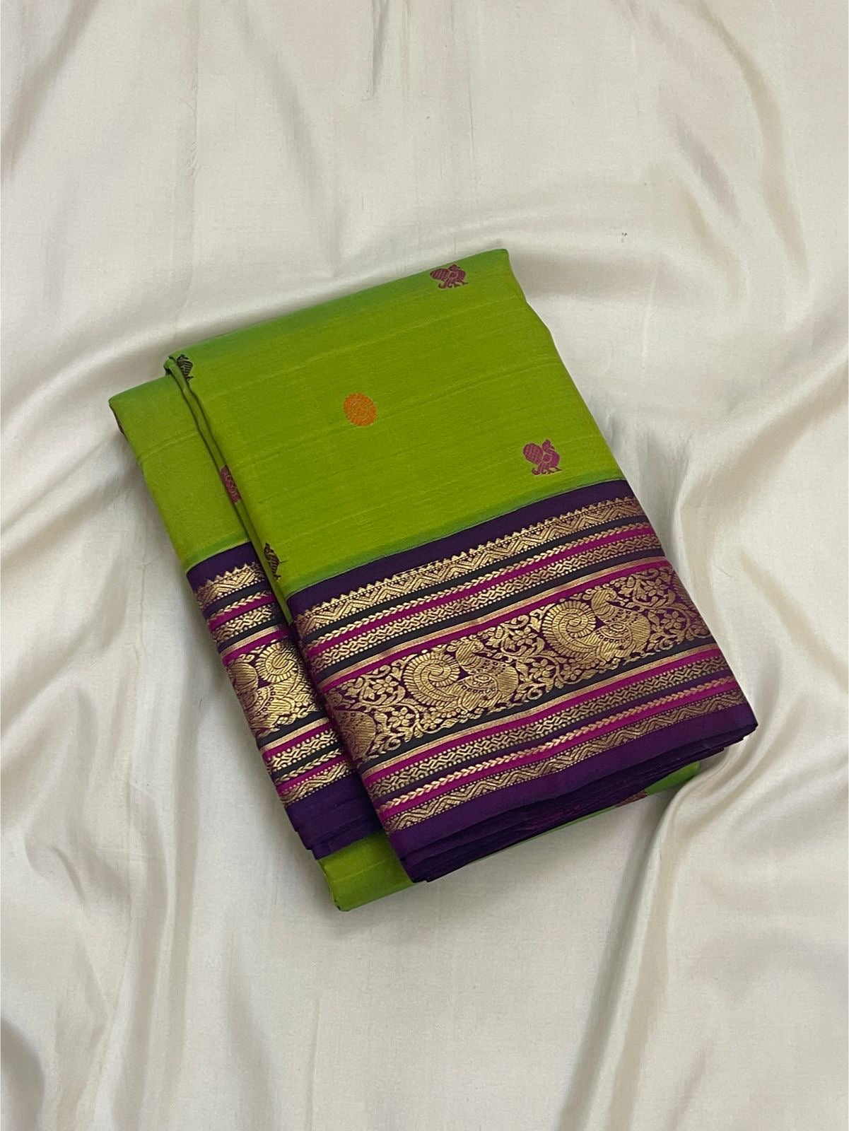 Parrot Green Pure Silk Kanchipuram saree with colourful silk-thread buttas, Deep Purple border and intricate gold Mayil motifs.