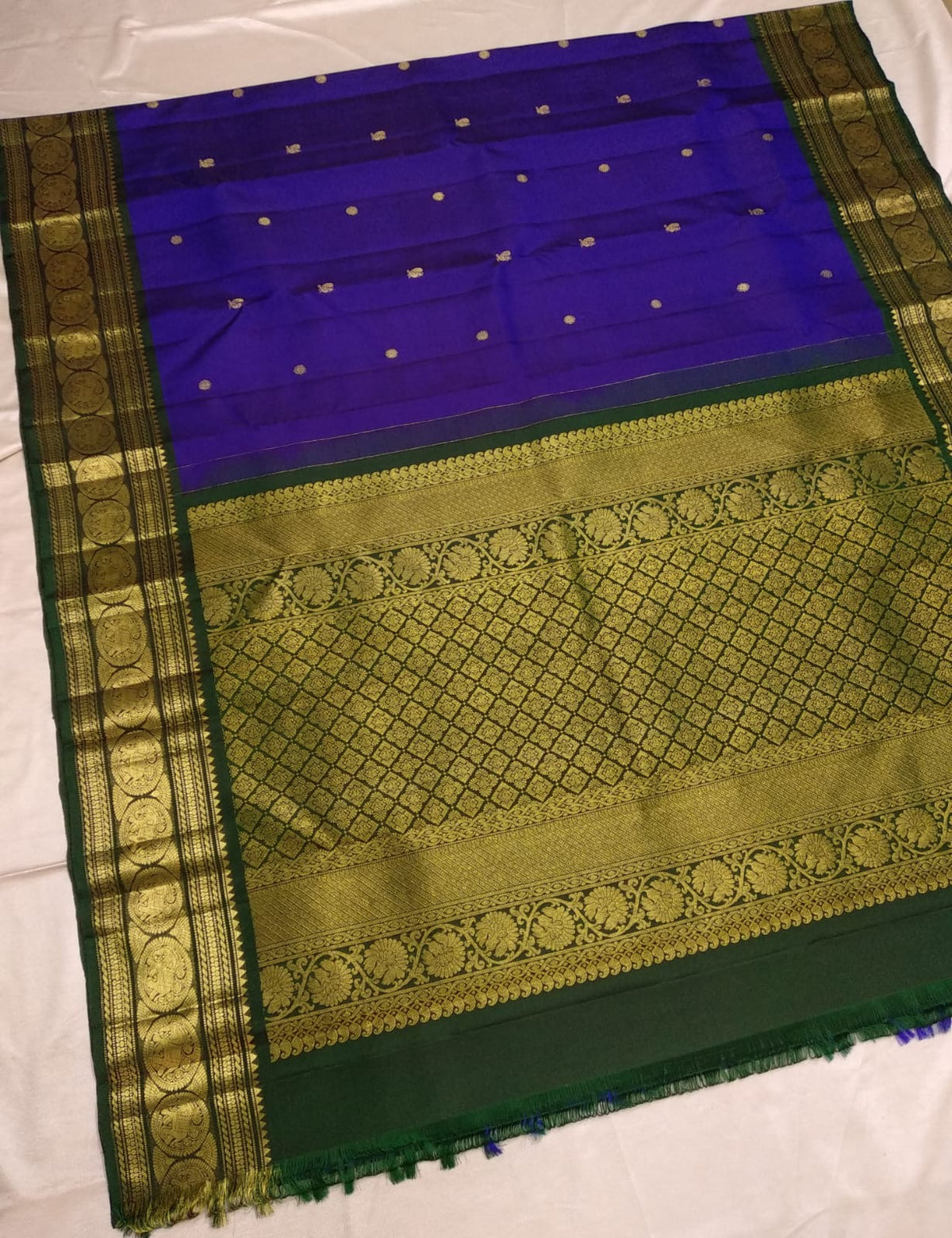 Royal-violet Kanchipuram silk saree spread open with petite Mayil and Kamalam buttas and broad gold Sorgavaasal border.