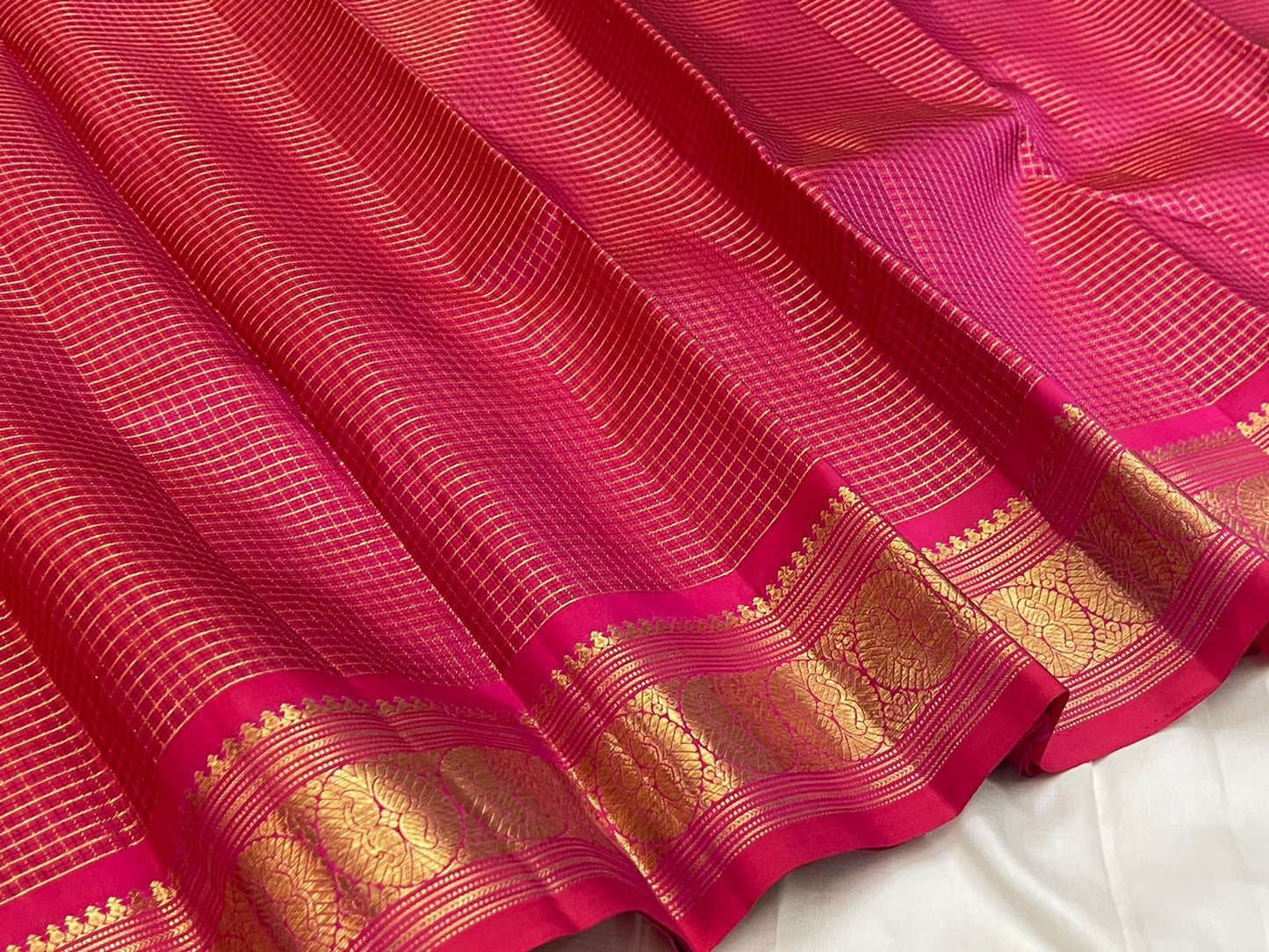 Close view of radiant pink Kanjivaram saree body with Pavun butta in gold zari kattam grid — Idam Living