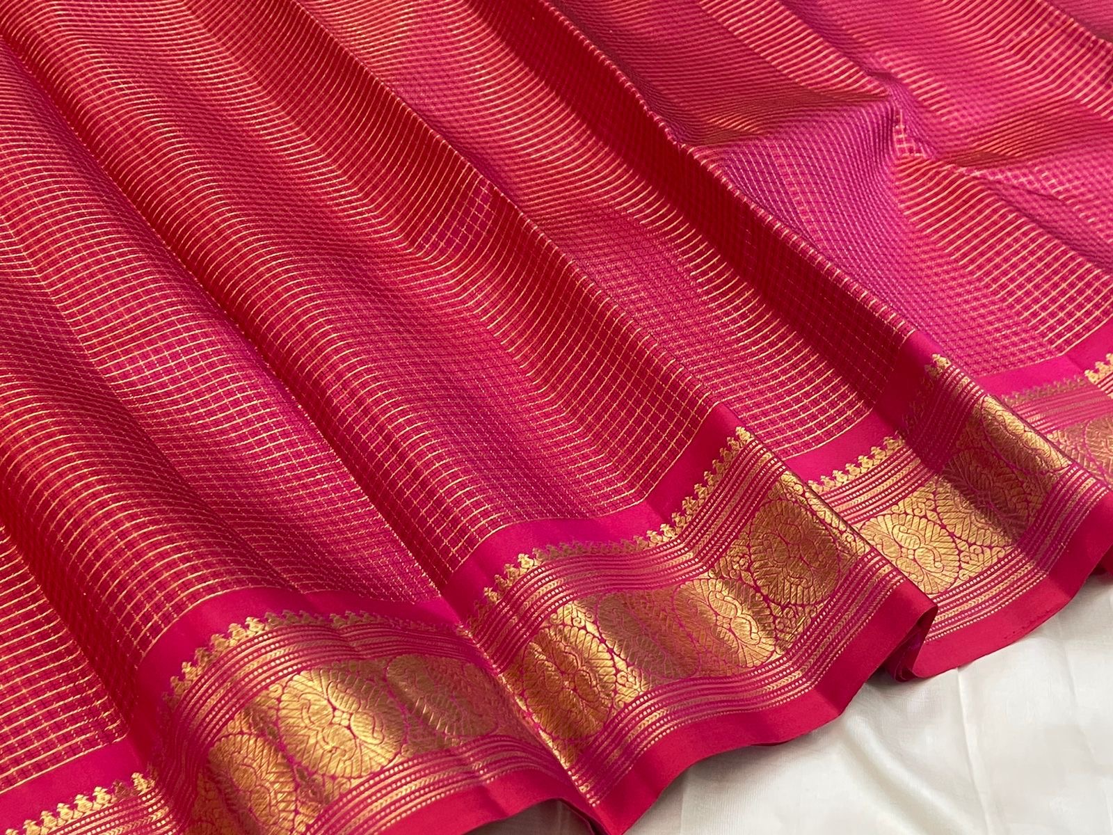 Close view of radiant pink Kanjivaram saree body with Pavun butta in gold zari kattam grid — Idam Living