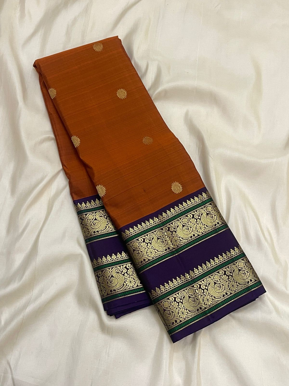 Laid-out Kanakambaram orange and purple Kanchipuram silk saree showing the contrast Rettapet and pallu.