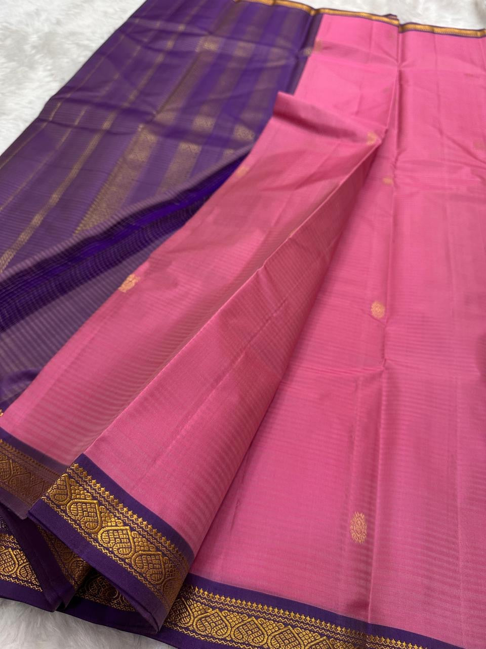 Pure Kanchipuram Silk Saree laid flat showing rose pink body with gold buttas and deep purple pallu with zari woven lines