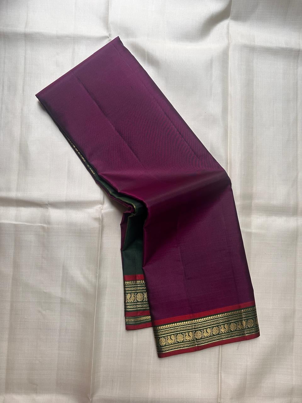 Green and purple pure Kanchipuram silk saree laid open showing narrow antique gold zari border and contrast color division