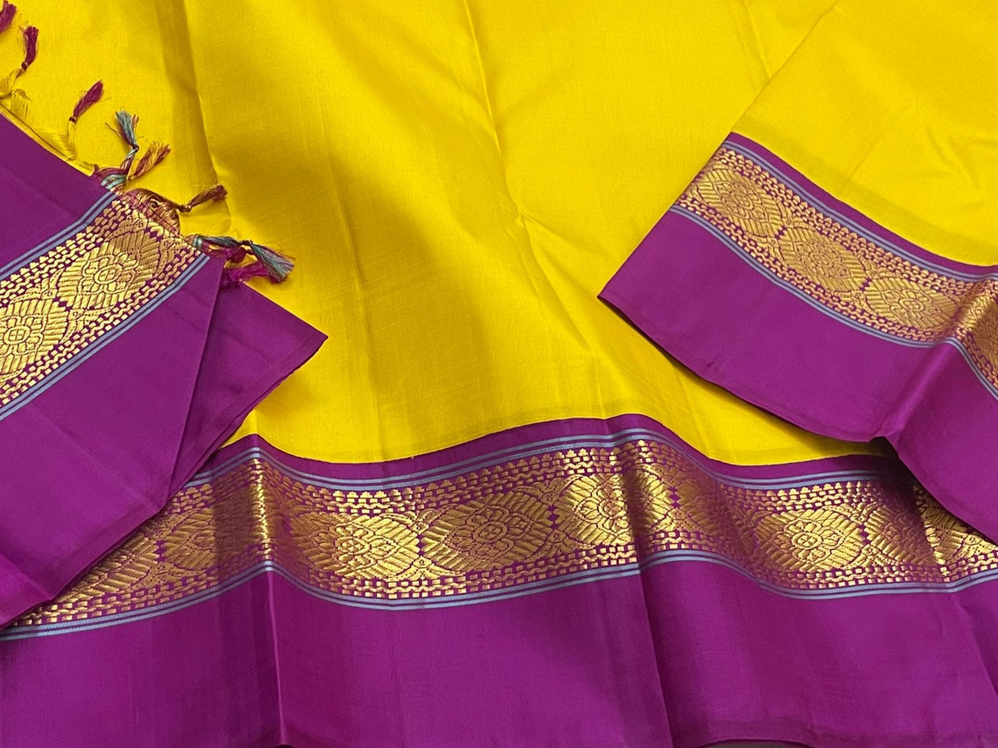 Close view of purple border with gold zari woven motifs on a yellow pure Kanchipuram silk saree