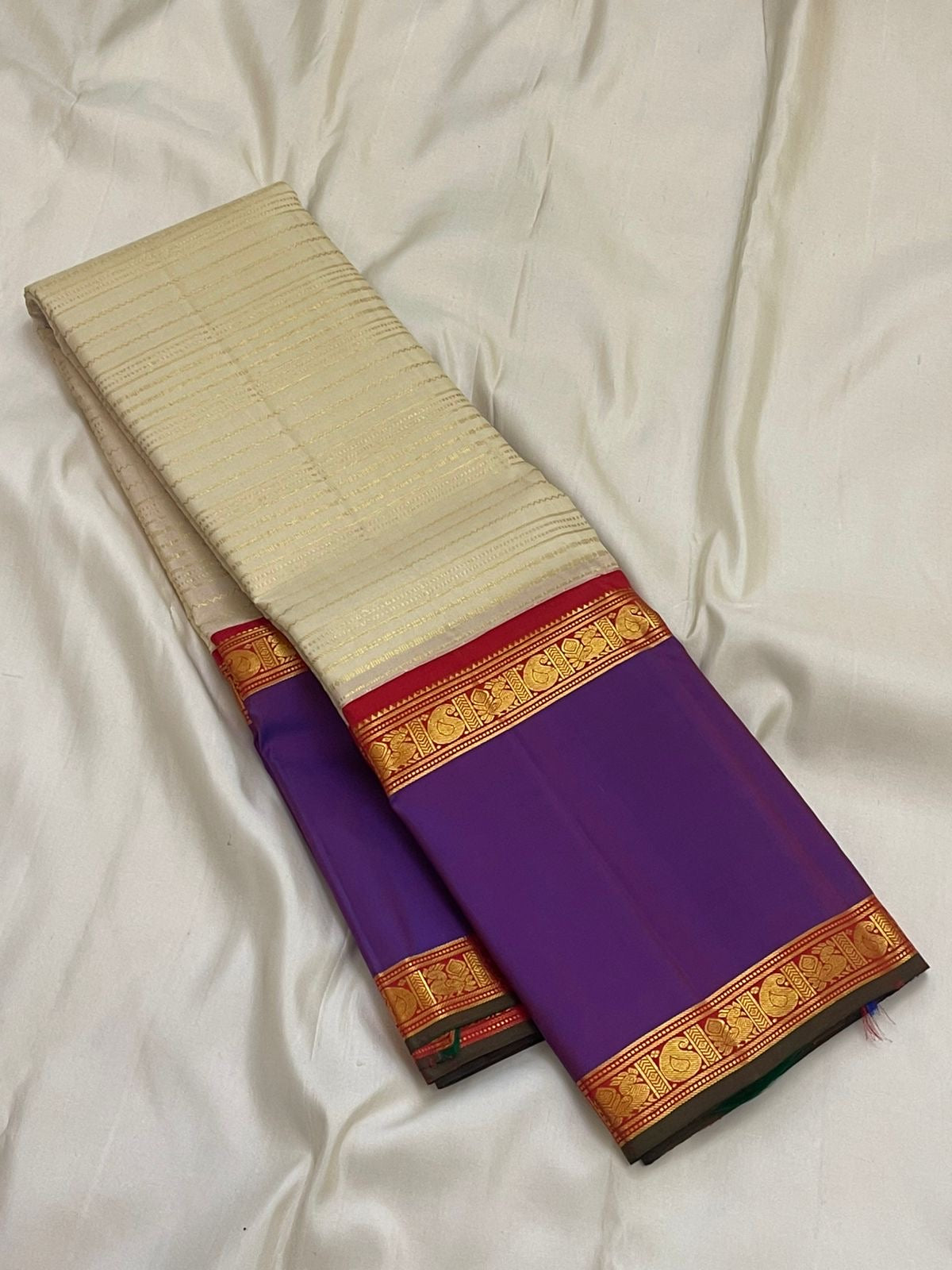 Pure Kanchipuram silk saree with ivory body featuring subtle zari stripes and contrast purple border