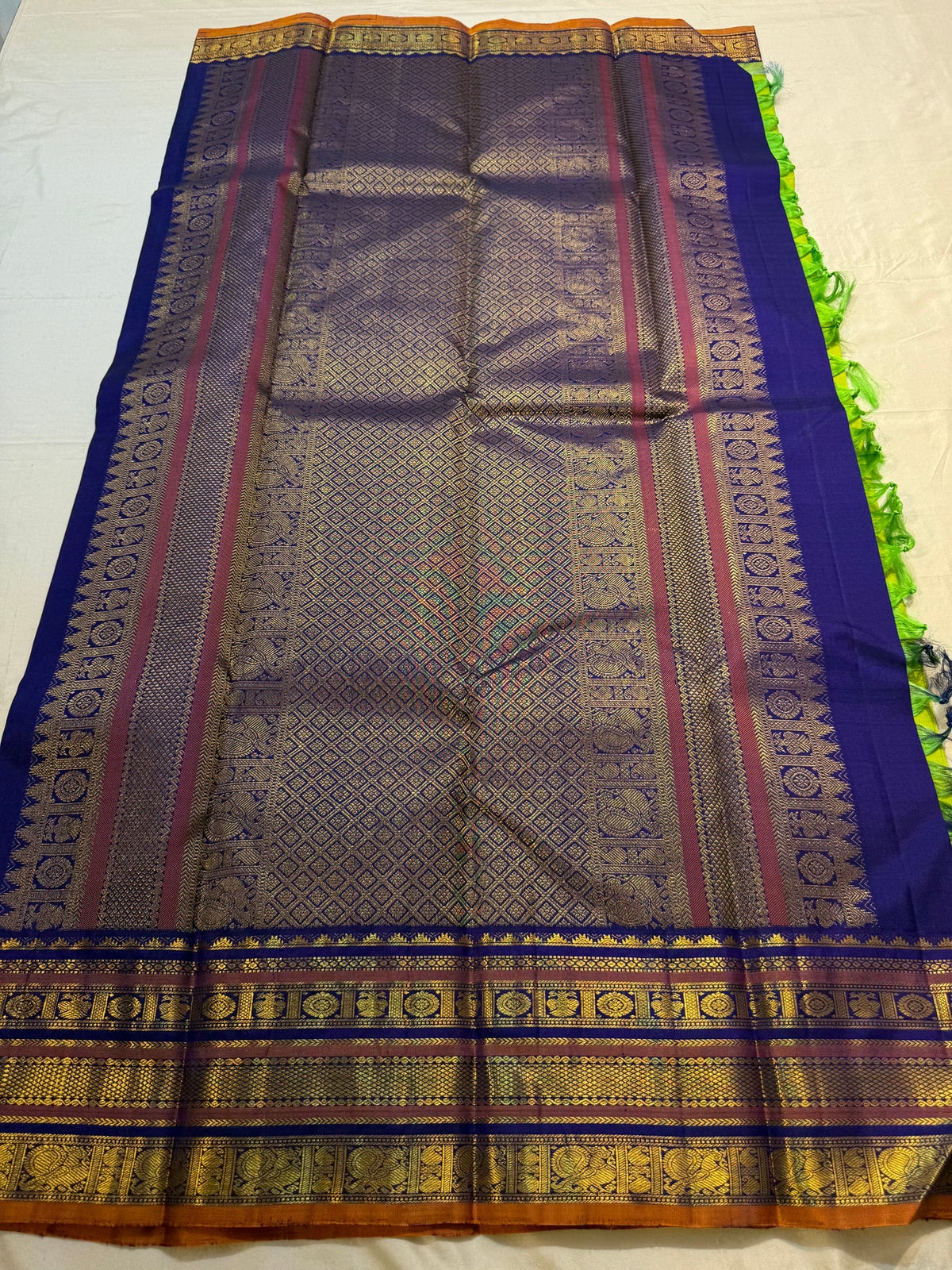 Varisaipet border detail showing layered gold zari bands against vivid lime-green Kanchipuram silk.