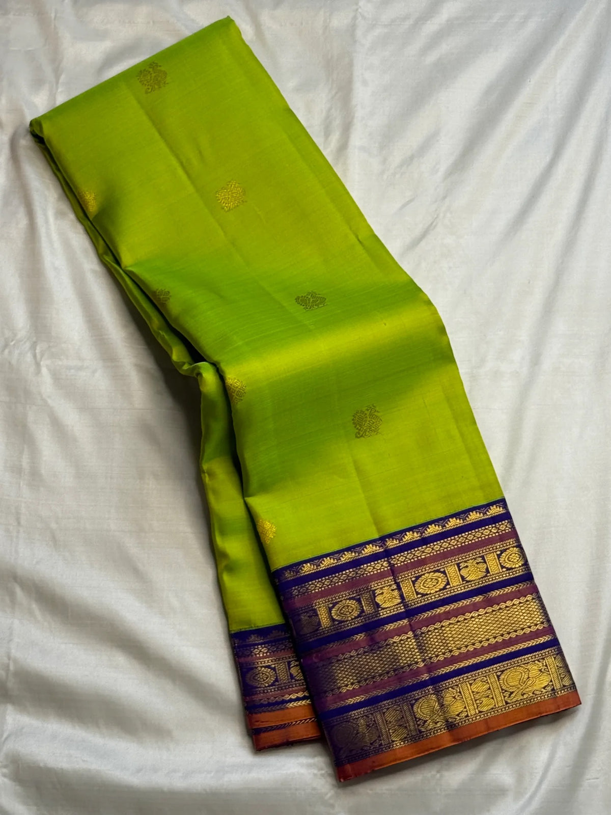 Handwoven green Kanchipuram saree showing scattered petite gold-toned zari buttas.