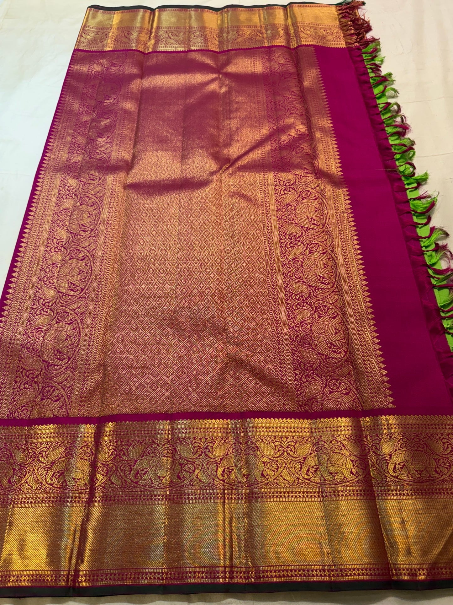 Close view of handwoven elephant zari border on Pachai Green and Rani Pink Kanjivaram silk.