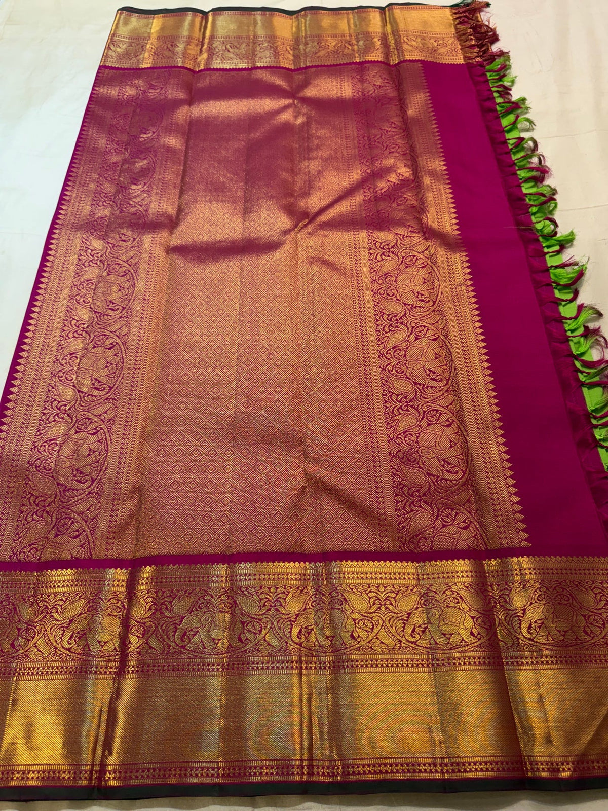 Close view of handwoven elephant zari border on Pachai Green and Rani Pink Kanjivaram silk.